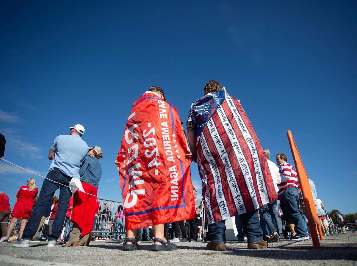 Jacob Sisk and Tony Allen wear flags draped over their shoulders while waiting in line prior to a campaign rally held by former President and Republican presidential candidate Donald Trump at First Horizon Coliseum in Greensboro, N.C. on Saturday, Nov. 2, 2024.