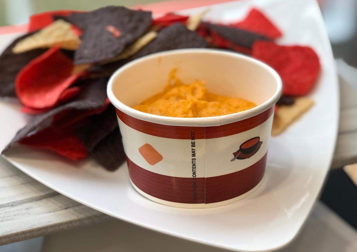 Cheese chicken and chili dip with tri-color tortilla chips.