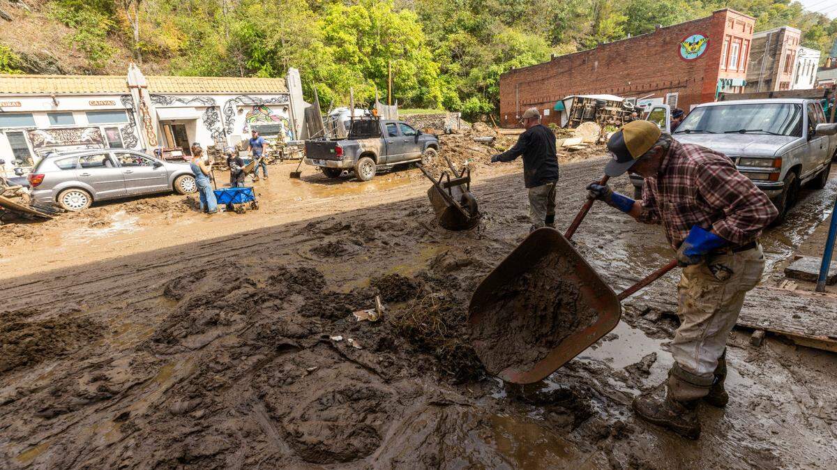 Residents and volunteers clean up on Tuesday, Oct. 1, 2024 after the French Broad River flooded downtown Marshall. The remnants of Hurricane Helene caused widespread flooding, downed trees, and power outages in western North Carolina.