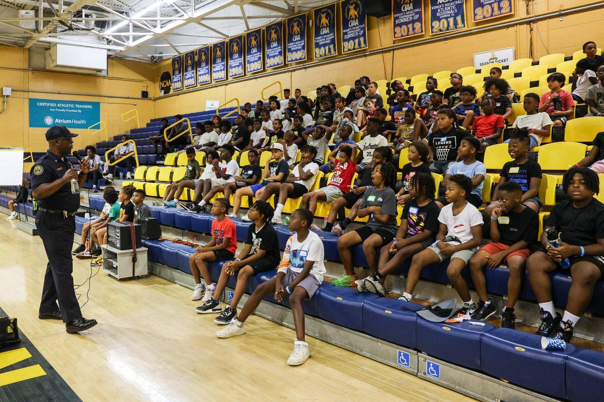 The junior varsity group of boys, ages 8-10 years old, listen as Capt. Brian Cunningham talks about the importance of school during Impact Camp at Johnson C. Smith University in Charlotteon Monday, July 21, 2025. Impact Camp offers 300 spots for a week-long free camp based in teaching young boys the importance of education, entrepreneurship, enlistment, employment and that there are many different positive paths in their lives.