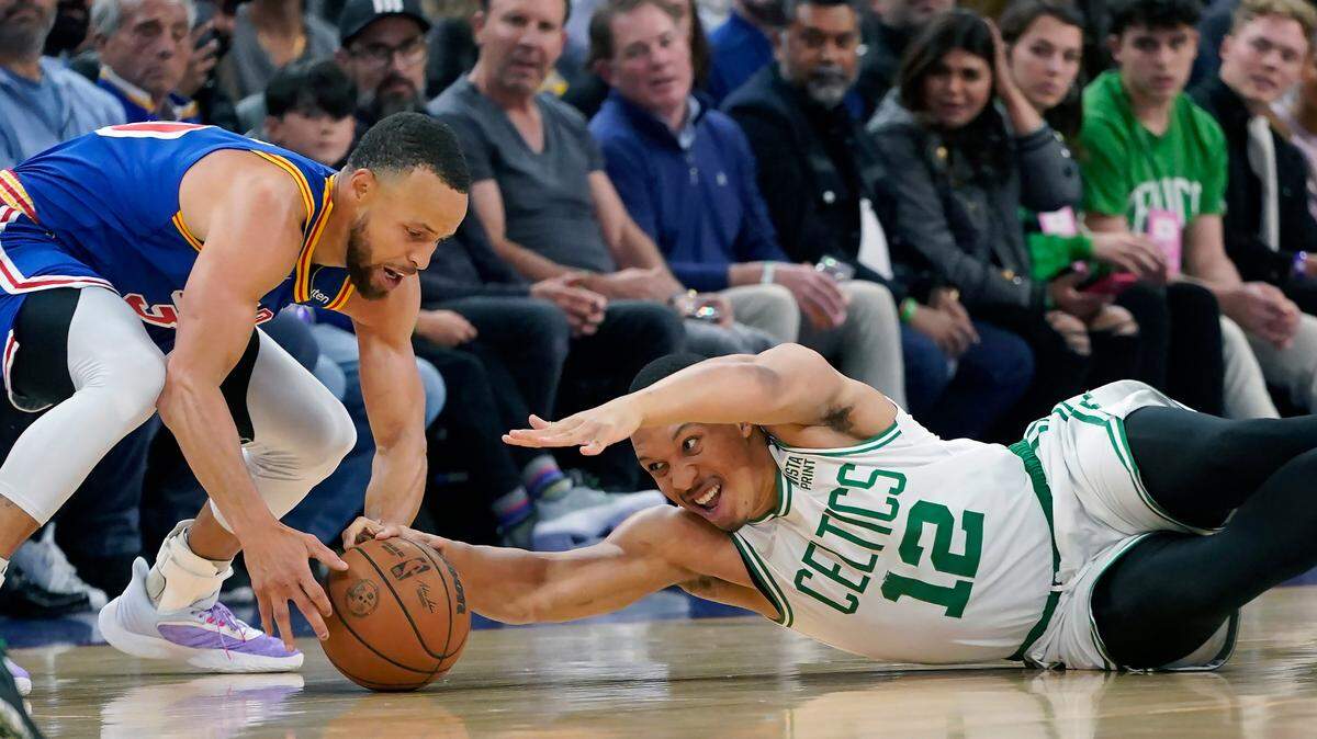 Golden State Warriors guard Stephen Curry, left, reaches for the ball next to Boston Celtics forward Grant Williams during the first half of an NBA basketball game in San Francisco, Wednesday, March 16, 2022. (AP Photo/Jeff Chiu)