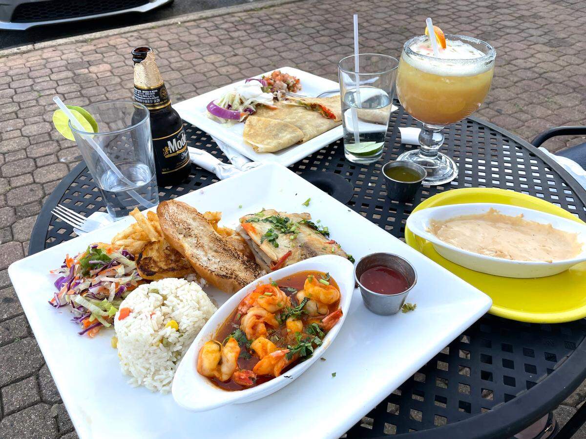 La Riviera Marisqueria serves Mexico’s coastal cuisine. Shown in the foreground is a Guamuchil seafood platter, with Guamuchil fish and shrimp served with salad, fries, rice, garlic bread and pico de gallo. A quesadilla, queso, a margarita and a Modelo are also pictured.