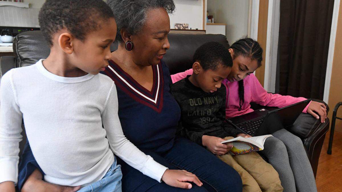 Regina Barrett, center, sits with her grandchildren Asa Barrett, left, 5, Hallie Barrett, 10, and Asher Barrett, 8, in her Monroe, NC home on Wednesday, February 10, 2021. Regina Barrett began juggling the roles of grandmother, caregiver and teacher to help out when the pandemic shutdown schools last year.