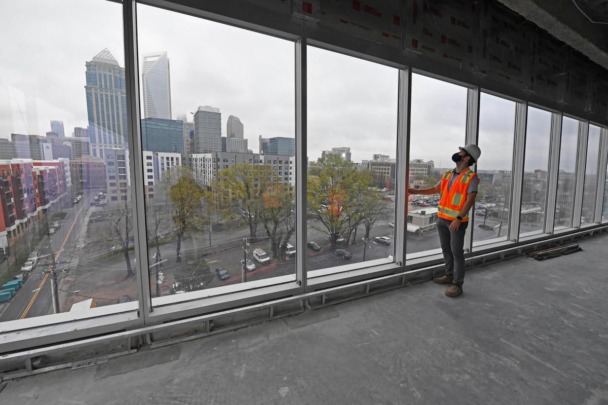 A Spectrum Companies executive looks out on the uptown Charlotte skyline view as construction progressed in March 2021 at the mixed-use Vantage South End project. The property includes two 11-story office towers, retail, a one-acre courtyard and plans for a hotel. The east office tower is set for completion in early 2022.