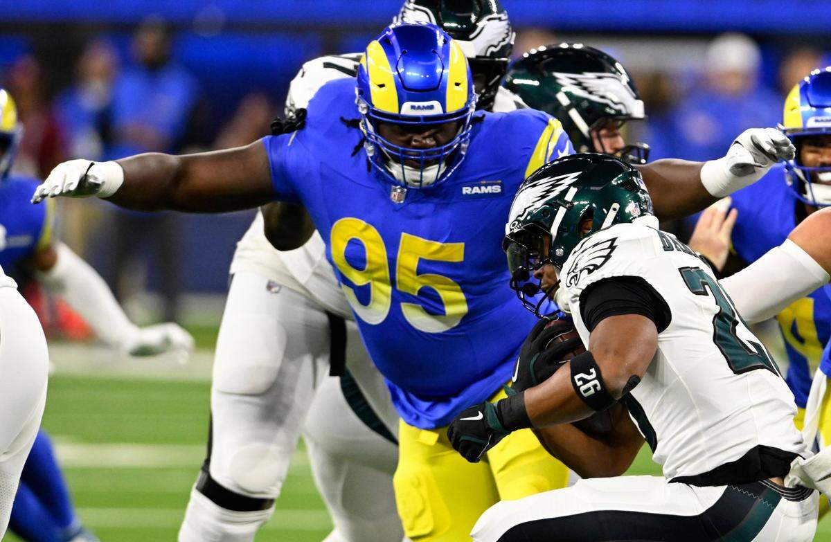 Nov 24, 2024; Inglewood, California, USA; Los Angeles Rams defensive tackle Bobby Brown III (95) tackles Philadelphia Eagles running back Saquon Barkley (26) during the first half at SoFi Stadium. Mandatory Credit: Alex Gallardo-Imagn Images