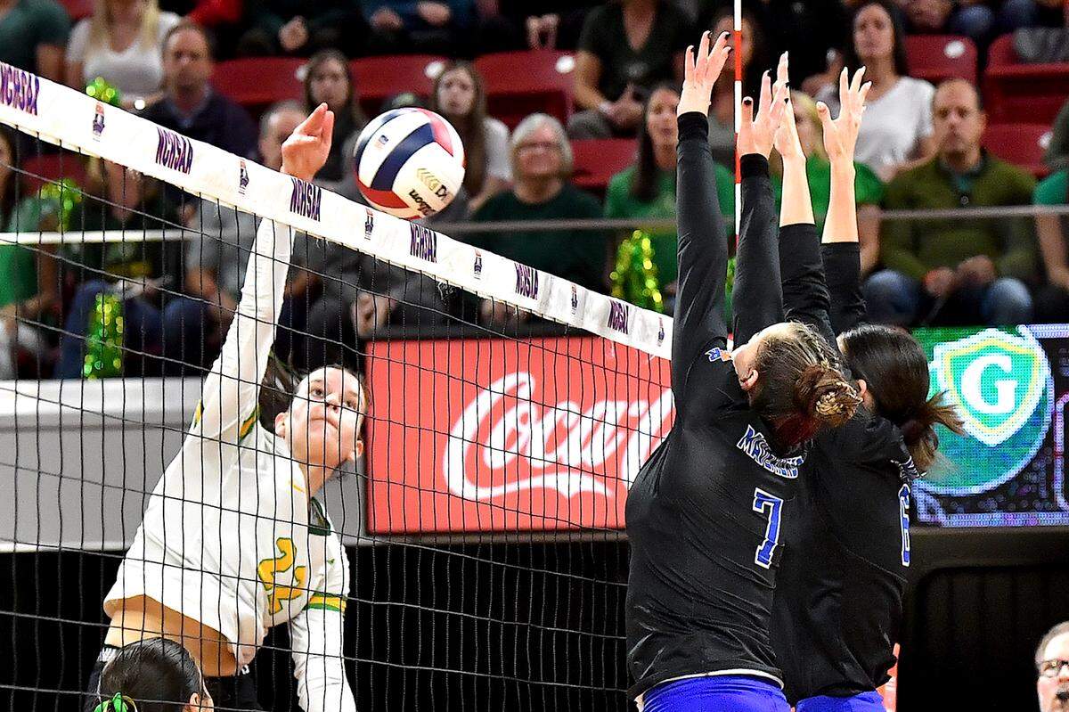 Cardinal Gibbons’ Mary Grace Gonyeau (22) spikes the ball against Marvin Ridge’s Kiley Petras (7) and Karsyn Baylog (6) in the 2024 NCHSAA 4A Volleyball Championships. The Marvin Ridge Mavericks took on the Cardinal Gibbons Crusaders in the NCHSAA 4A Volleyball Championship match in Raleigh, N.C. on November 2, 2024.