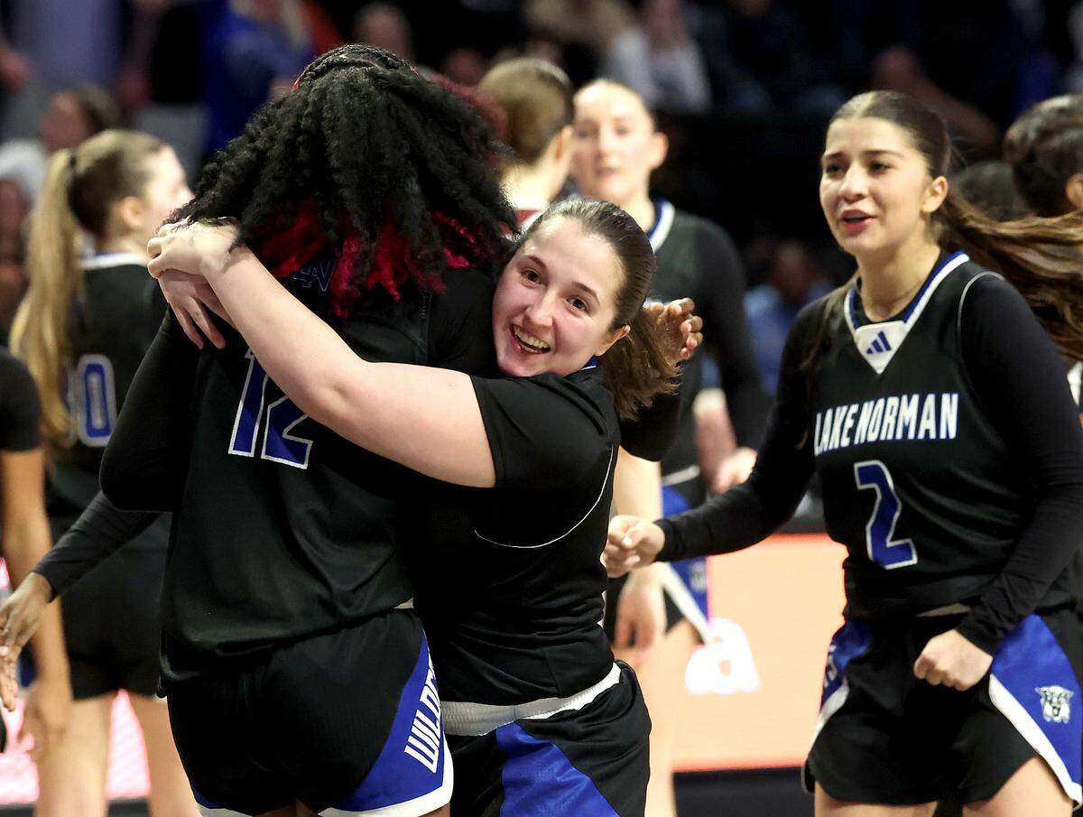 Lake Norman’s Rayana Minard, left/back to camera, is grabbed by her teammates as they begin to celebrate their 43-41 victory over Wakefield in the girls NCHSAA 4A State Championship game on Saturday, March 15, 2025 at Lawrence Joel Veterans Memorial Coliseum in Winston-Salem, NC.