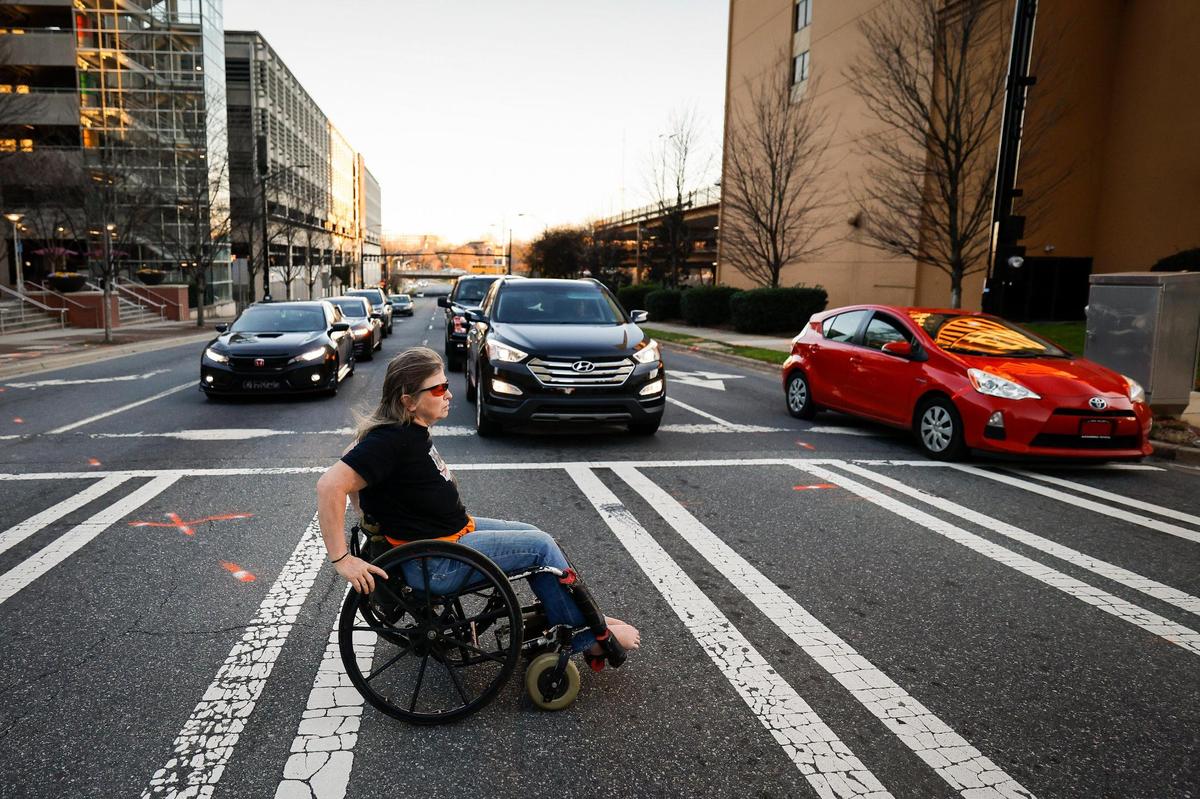 Barbara Ryan crosses East Fourth Street in uptown Charlotte on March 1, near the parking deck elevator where she was forced to sleep after losing her home in February 2019. Ryan, who is paralyzed from the waist down and legally blind, was forcibly evicted for back taxes that two courts have found that she already paid.