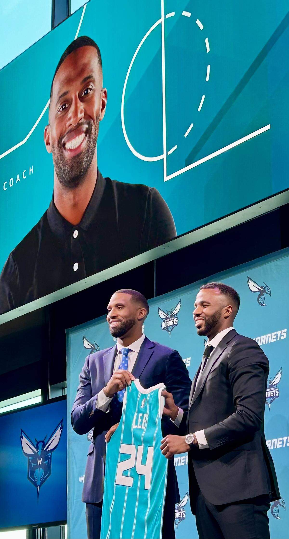 New Charlotte Hornets coach Charles Lee (left) and Hornets’ general manager Jeff Peterson hold up a jersey with Lee’s name on Tuesday, June 25, 2024, at Lee’s opening news conference.