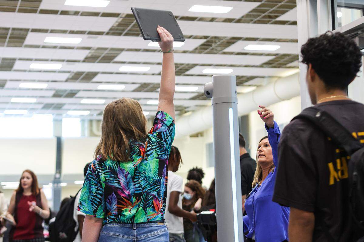 A student is instructed to raise their laptop above the metal detector as they enter the building for the first day of school at Palisades High School, a brand new CMS campus, on Monday, August 29, 2022 in Charlotte, NC.