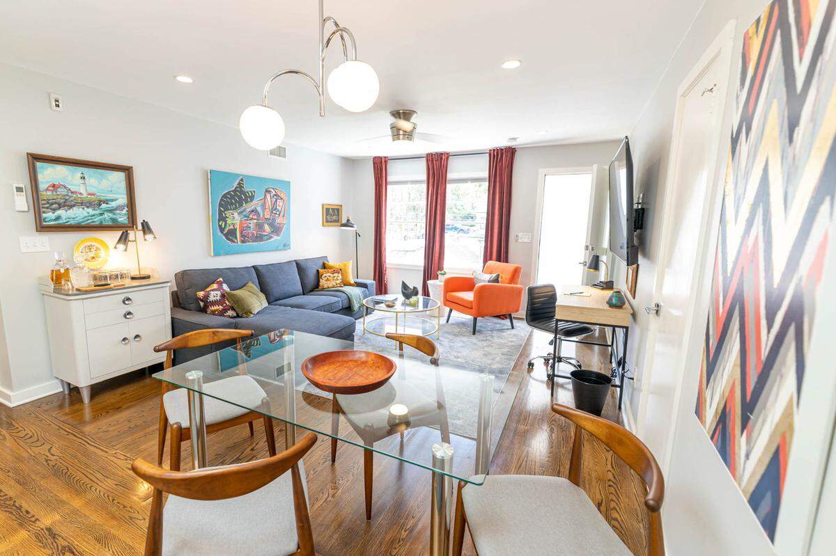 A living room at 510 Queens has art by Nico Amortegui above the couch and a paint-by-number from Sleepy Poet above the side table.