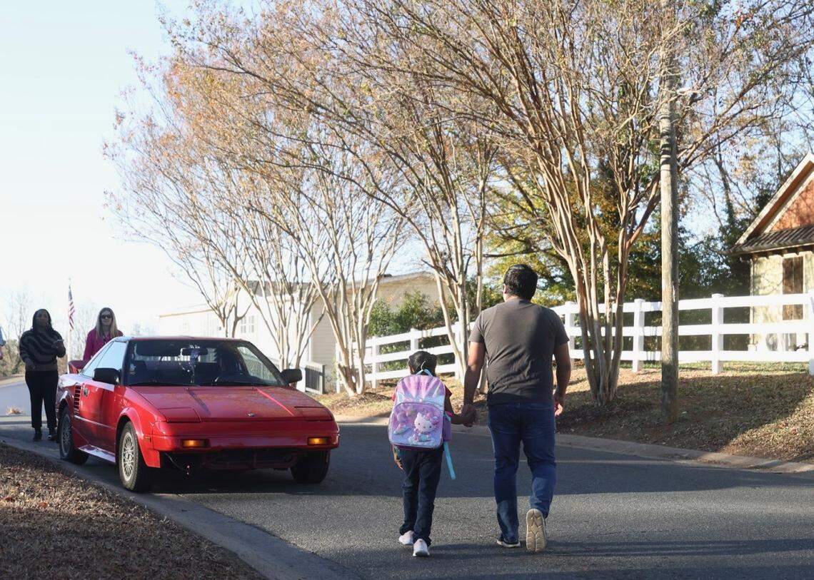 A parent walks her daughter home from a bus stop on Monday, November 17, 2025