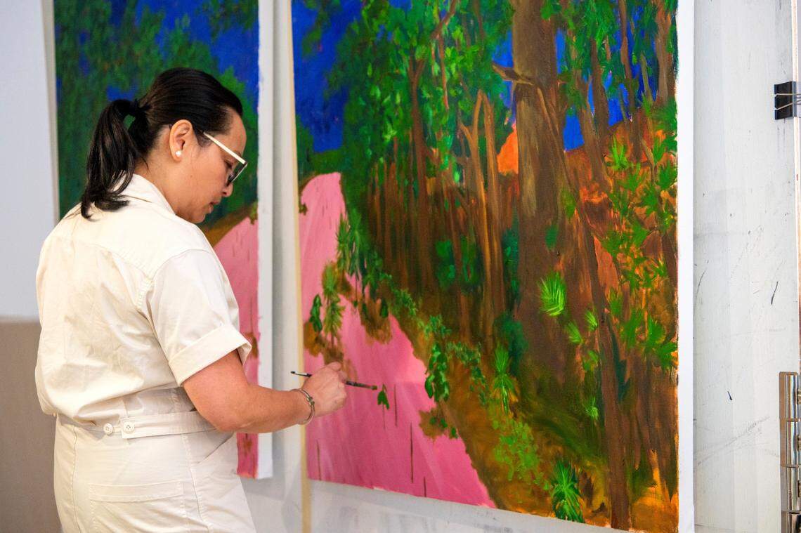 Artist Malu Tan works on a painting titled “There’s So Much Growth Here!” in her Charlotte studio. Tan is known for her vivid color palettes.