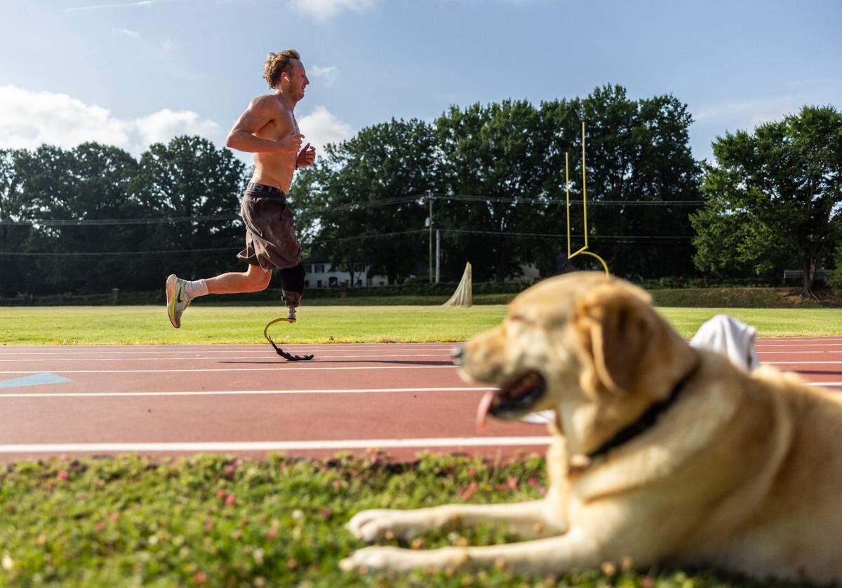 Carson Clough trains for the Paralympics triathlon while his service dog, Calder, keeps an eye on him at Alexander Graham Middle School in Charlotte, N.C., on Saturday, July 6, 2024.