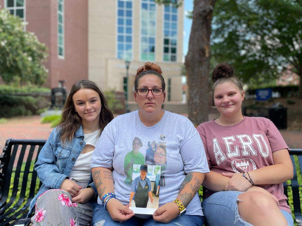 Promise Edwards, 37, sits between Kansas Evans, 18, (left) and Hannah Rhodes, 19, outside the Union County Judicial Center in Monroe, N.C. on Tuesday, Aug. 8, 2023. The three drove two hours from Laurens, S.C., for the expected appearance of the couple accused of killing their 18-year-old friend Jacob Williamson.