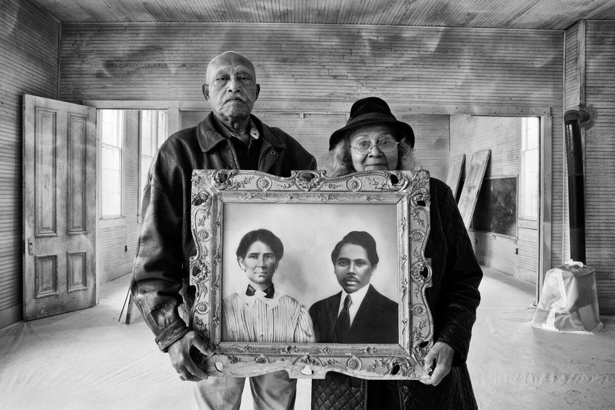 Elroy and Sophia Williams, at the Rosenwald Hopewell School in Bastrop County, Texas. They are holding a photo of her grandparents, Sophia and Martin McDonald, former slaves who donated land for the Hopewell school that Sophia Williams attended.