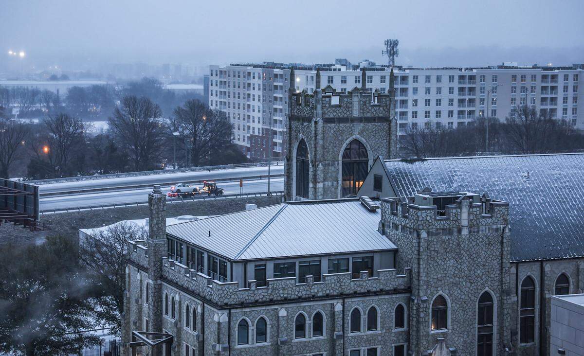 A tow truck in the distance hauls a vehicle along an ice-covered Interstate 277 on Sunday morning on January 25, 2026. 