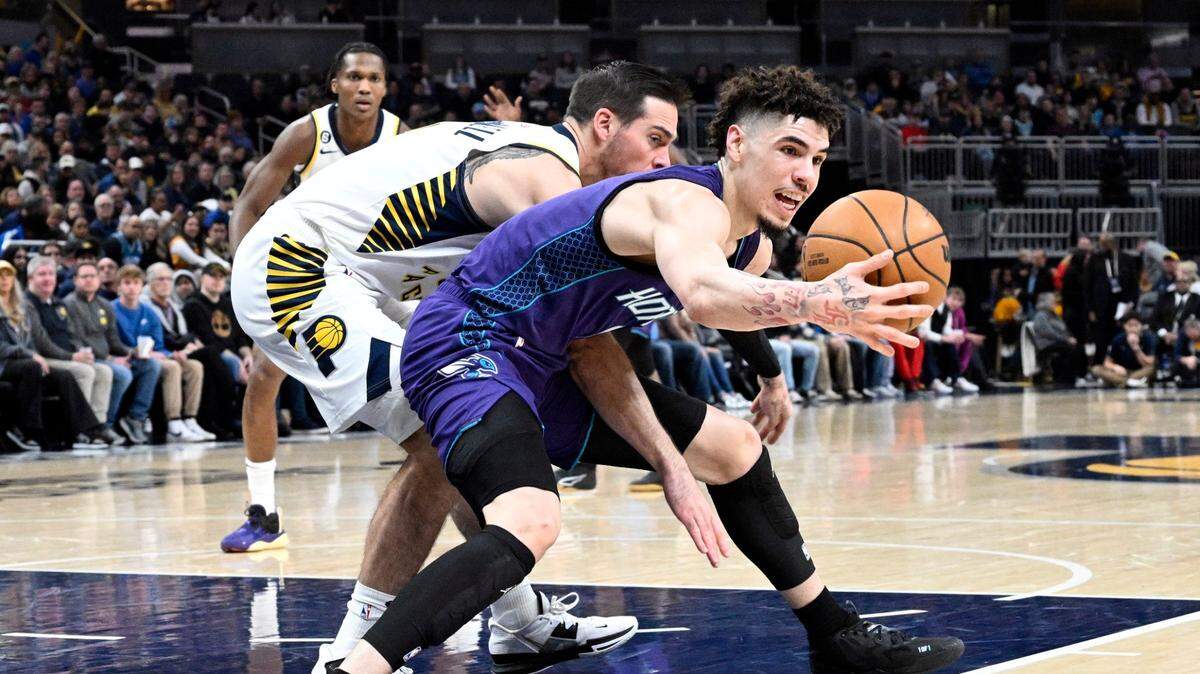 Charlotte Hornets guard LaMelo Ball reaches for a ball against Indiana Pacers guard T.J. McConnell during the first half of an NBA basketball game, Sunday, Jan. 8, 2023, in Indianapolis. (AP Photo/Marc Lebryk)