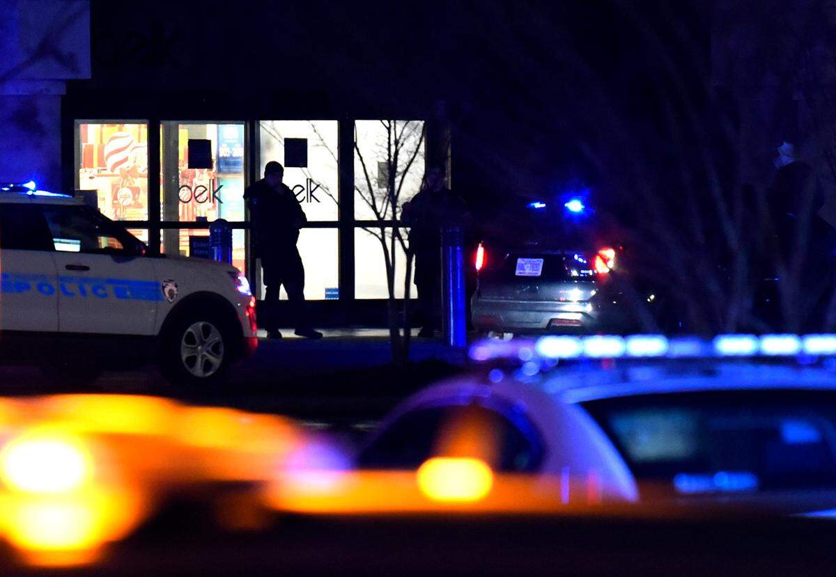 A police officer stands silhouetted in the doorway of the Belk store at Carolina Place Mall in Pineville, NC on Thursday, Dec. 24, 2020. Police responded after receiving over a dozen 911 calls reporting shots fired. Pineville Police said that they did not find anyone injured.