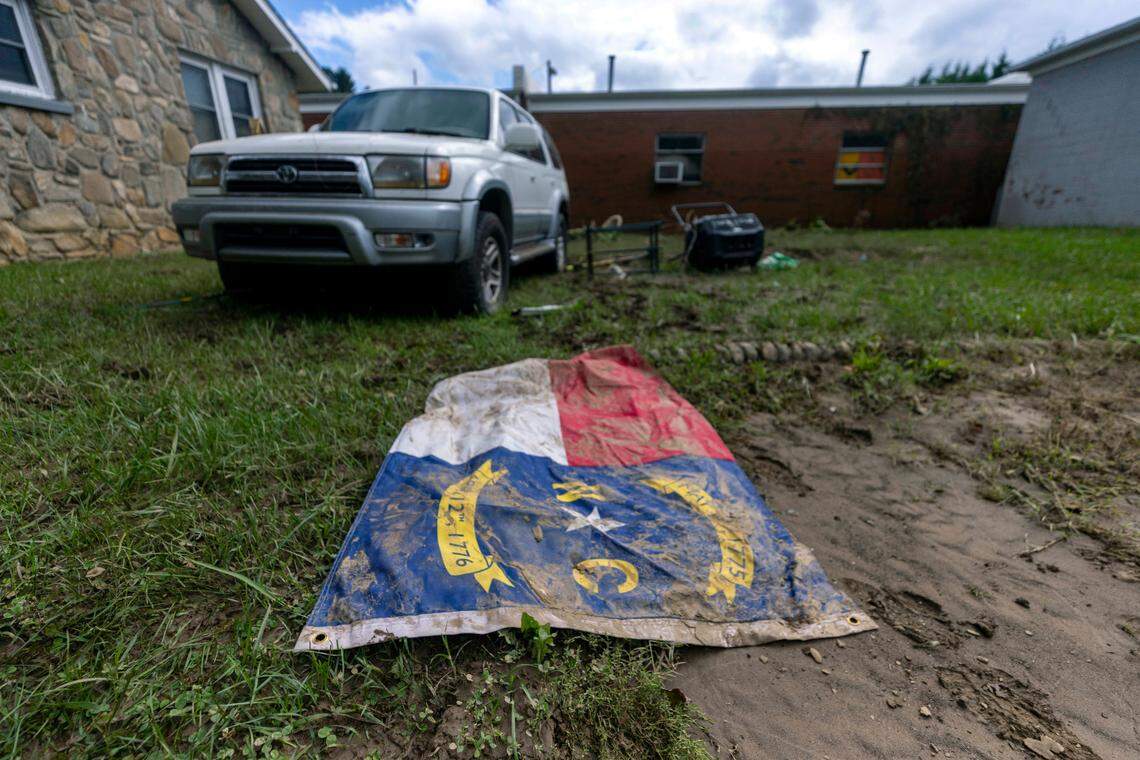A North Carolina flag llies in the mud in Clyde on Saturday, Sept. 28, 2024 after massive flooding damaged dozens of homes and businesses. The remnants of Hurricane Helene caused widespread flooding, downed trees, and power outages in western North Carolina.
