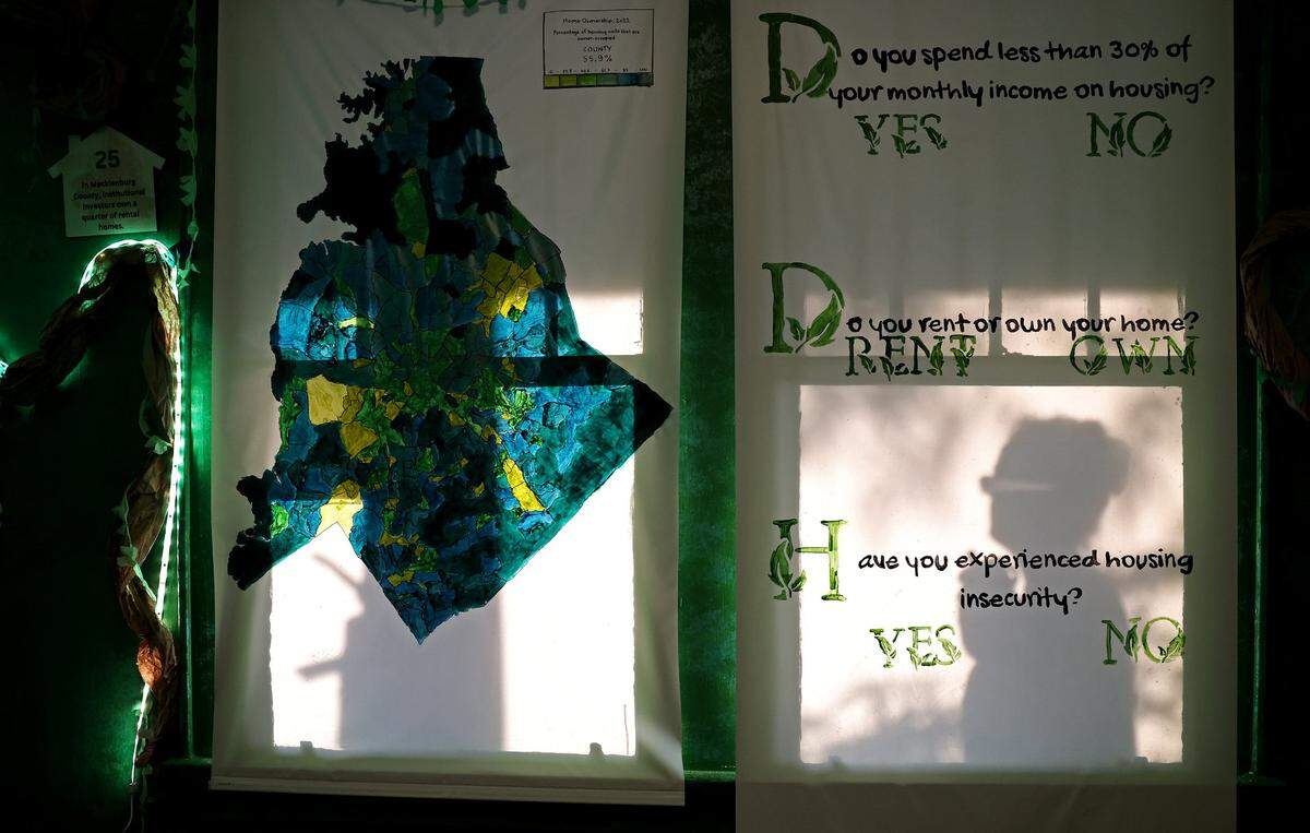Hazel Doherty, right, is silhouetted on the blind of a window with questions audience members will be asked to consider during an immersive play on gentrification. QC Family Tree’s Big Blue House in Charlotte, NC will be hosting the upcoming play.