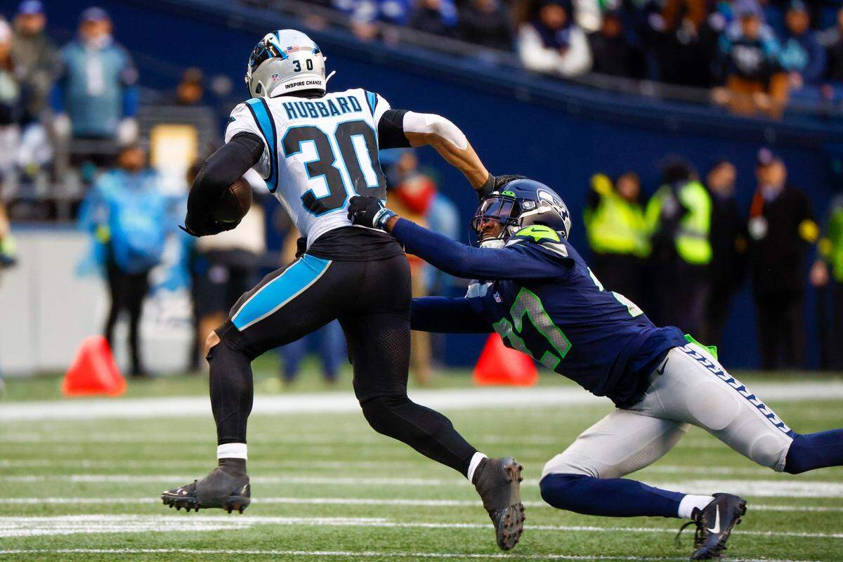 Dec 11, 2022; Seattle, Washington, USA; Carolina Panthers running back Chuba Hubbard (30) stiff arms a way from a tackle attempt by Seattle Seahawks cornerback Tariq Woolen (27) during the fourth quarter at Lumen Field. Mandatory Credit: Joe Nicholson-USA TODAY Sports