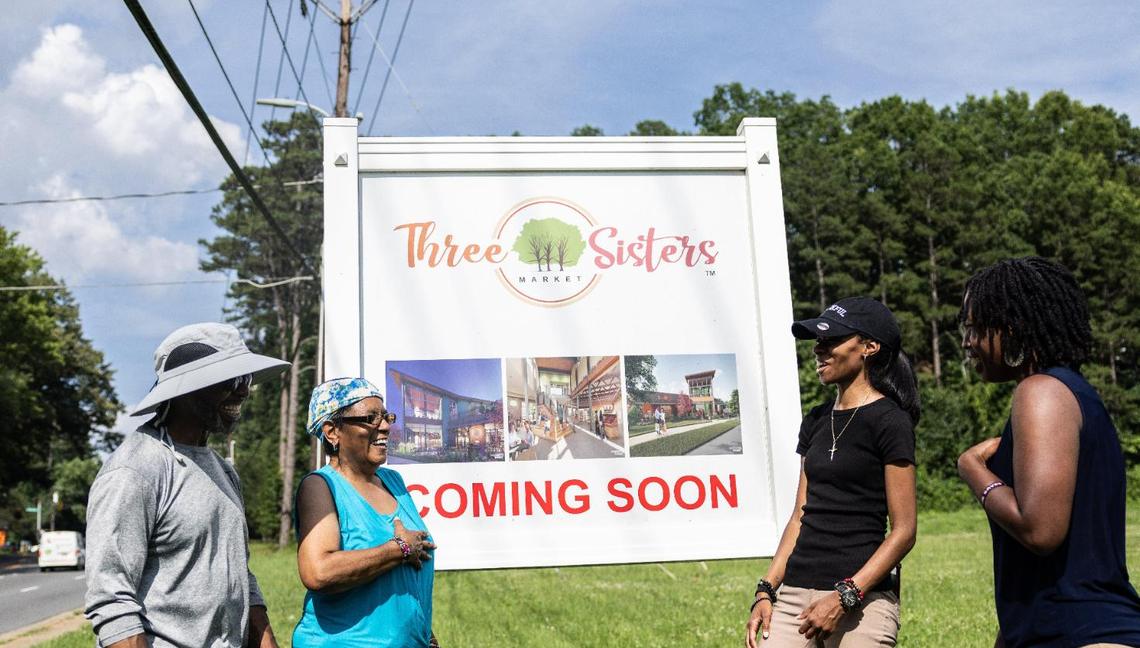 From left, Rickey Hall, West Boulevard Neighborhood Coalition board chair, vice chair Brenda Campbell, executive director Sharika Comfort and D’Asia Feaster, neighborhood ambassador, at a sign for the future grocery co-op Three Sisters in Charlotte. The co-op aims to fill a need in the west Charlotte community.
