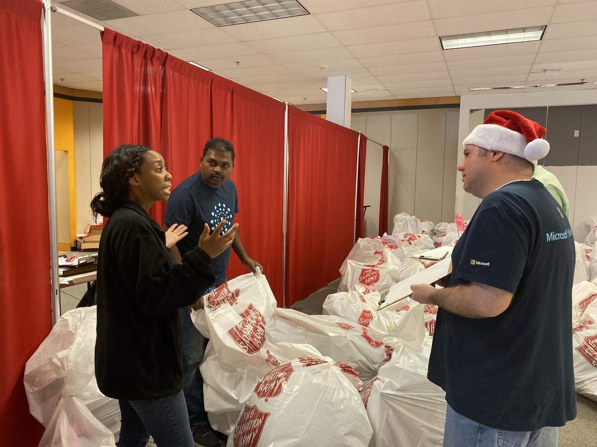 Velegar Curry, the Salvation Army Christmas Center volunteer coordinator, gives instruction to two volunteers from Microsoft, Ramesh Boddu and Brennan Mann.