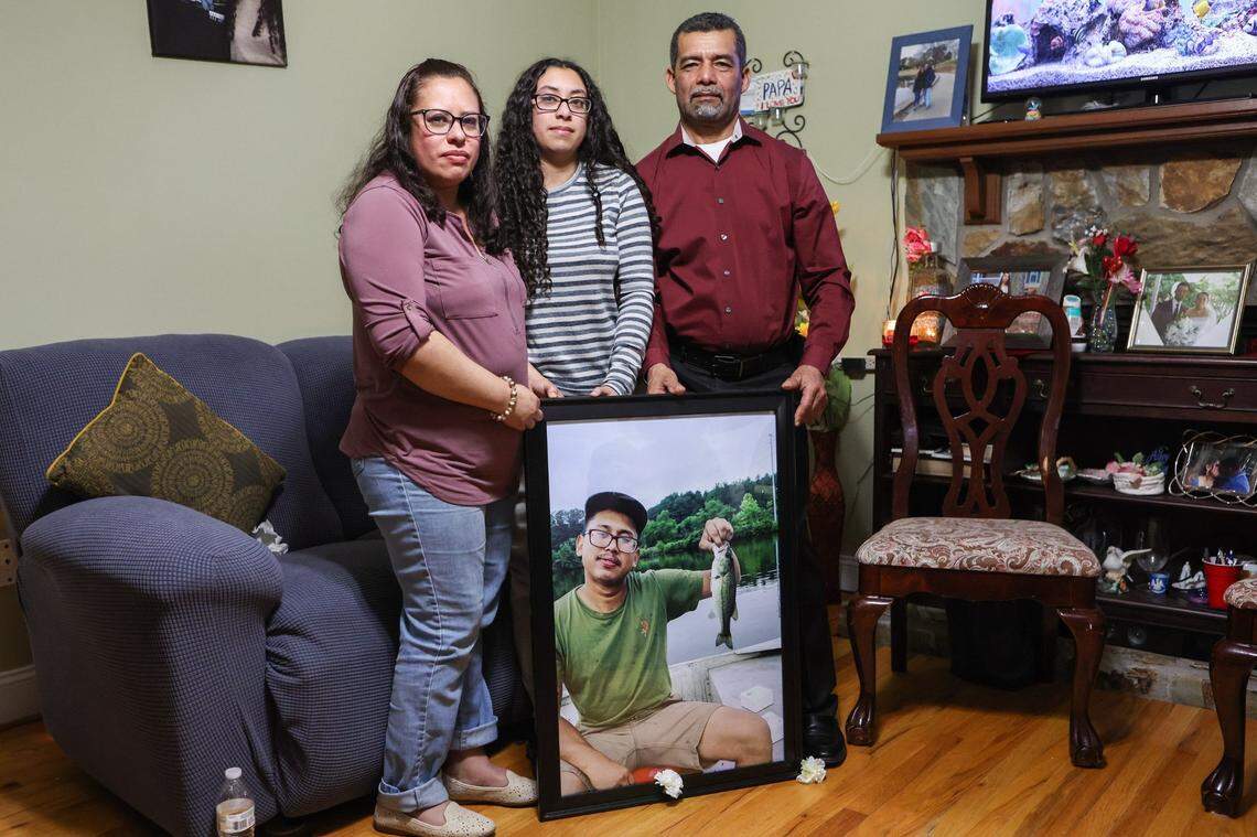 Iris Bonilla, left, lost her son, Jose Bonilla Canaca, in a scaffolding collapse earlier this year. Bonilla, her daughter Amy, and her husband Osman Reyes stand with a photo of Jose holding the first fish he’d caught. “Every day, there is a pain in my heart,” Iris said.