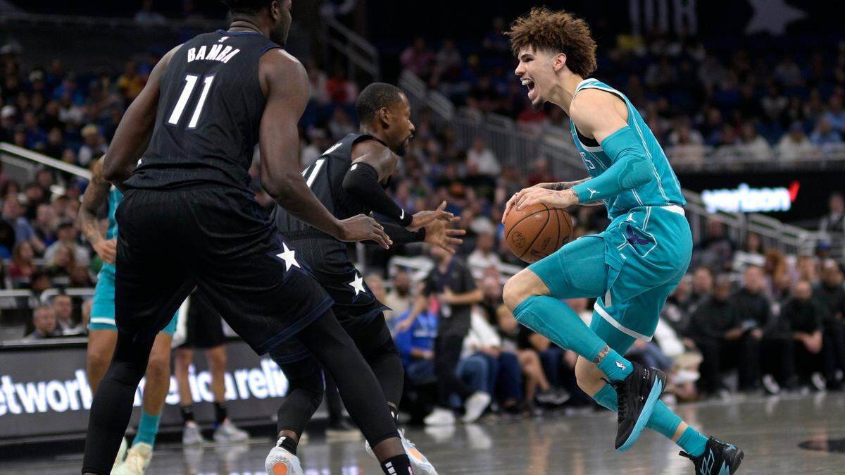 Charlotte Hornets guard LaMelo Ball, right, is defended by Orlando Magic center Mo Bamba (11) and guard Terrence Ross, center, during the first half of an NBA basketball game, Monday, Nov. 14, 2022, in Orlando, Fla. (AP Photo/Phelan M. Ebenhack)