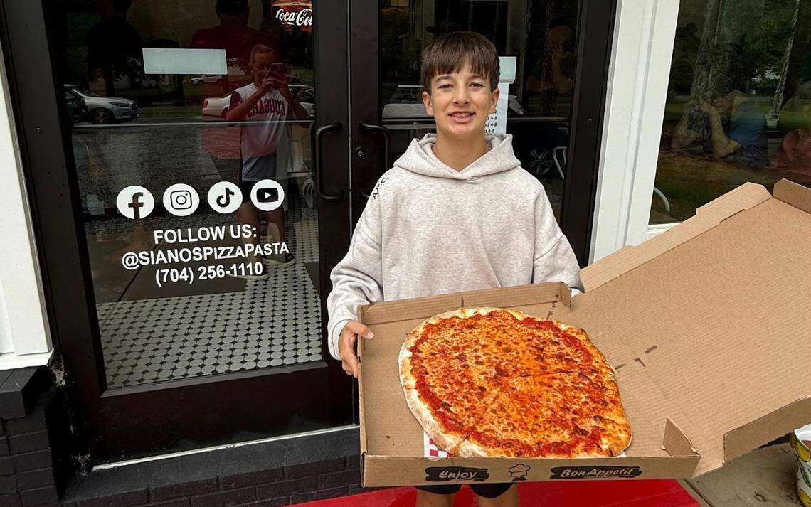Tristan Graziano holds an 18” cheese pizza outside Siano’s in Waxhaw.