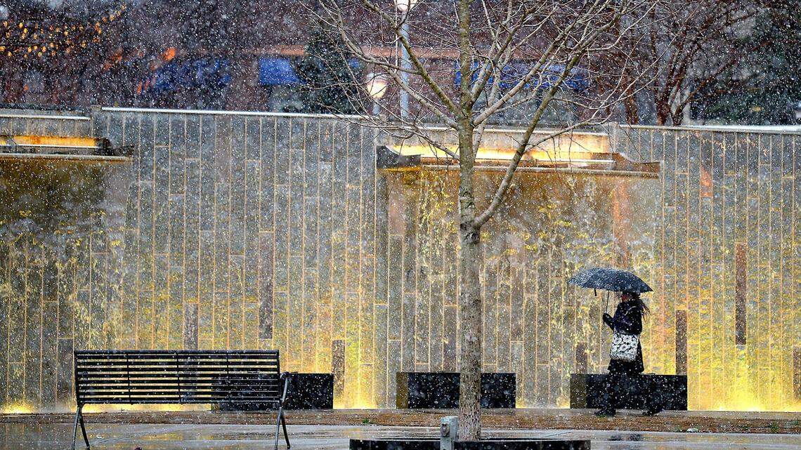 Feb. 20, 2020. An uptown Charlotte worker walks past the fountains at Romare Bearden Park as the snow falls in uptown Charlotte, NC on Thursday.