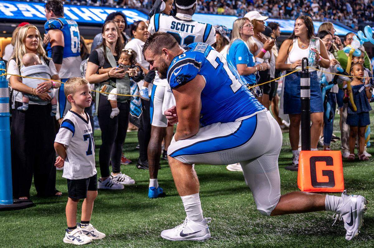 Carolina Panthers offensive lineman Brady Christensen kneels to talk with a young fan during the Carolina Panthers' fan fest at the Bank of America Stadium in Charlotte, NC, Saturday August 2, 2025.