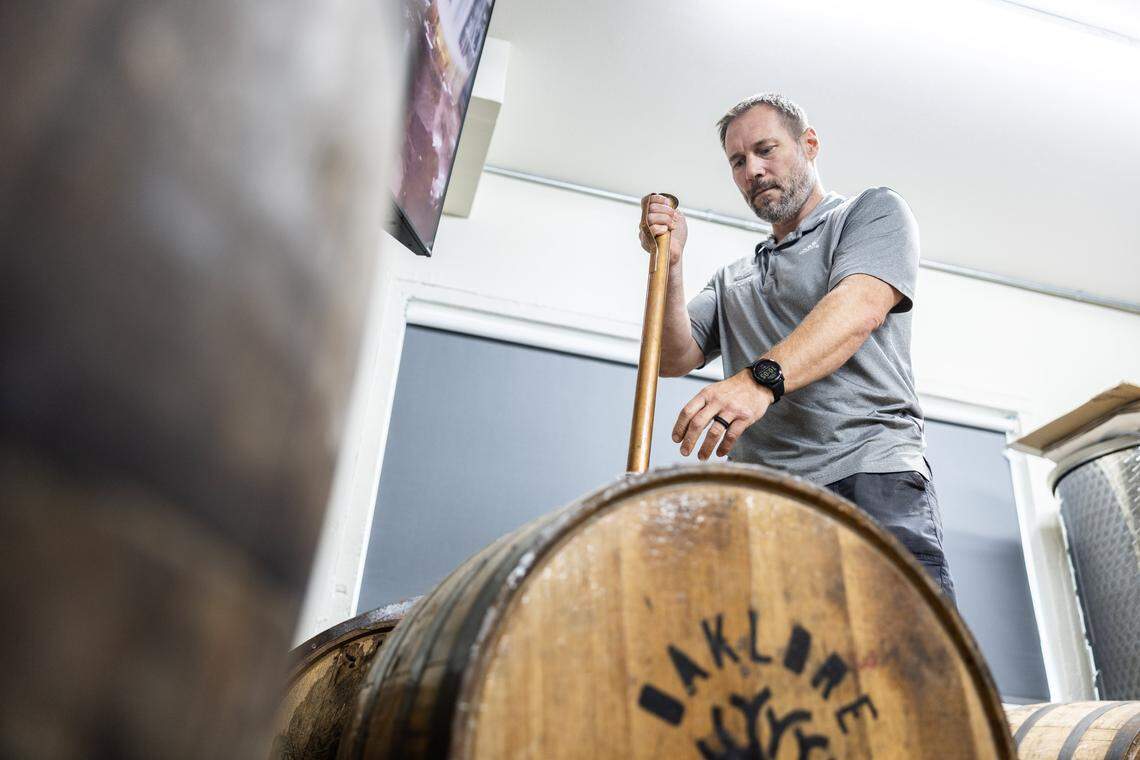 Tom Bogan gets a sample of a coffee liqueur out of a barrel at Oaklore Distilling Co. in Matthews, N.C., on Tuesday, September 30, 2025.