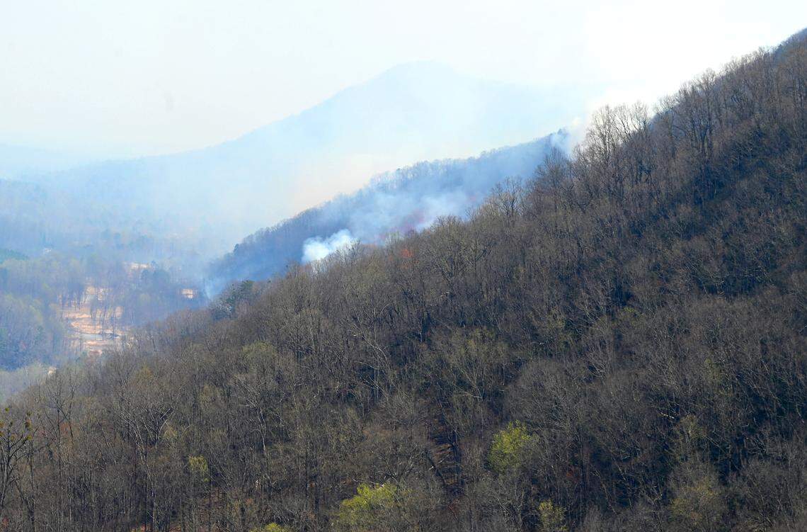 Smoke rises from the hillside of a mountain near Green River Cover Road in Saluda, N.C., on Thursday, March 27, 2025. Wildfires threatening the area have caused some roads to be closed.