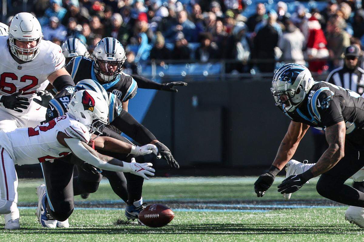 Cardinals runningback Michael Carter, front left, reaches for a loose ball as Panthers defense dives in as well during the game at Bank of America Stadium in Charlotte, NC on Sunday, December 22, 2024.