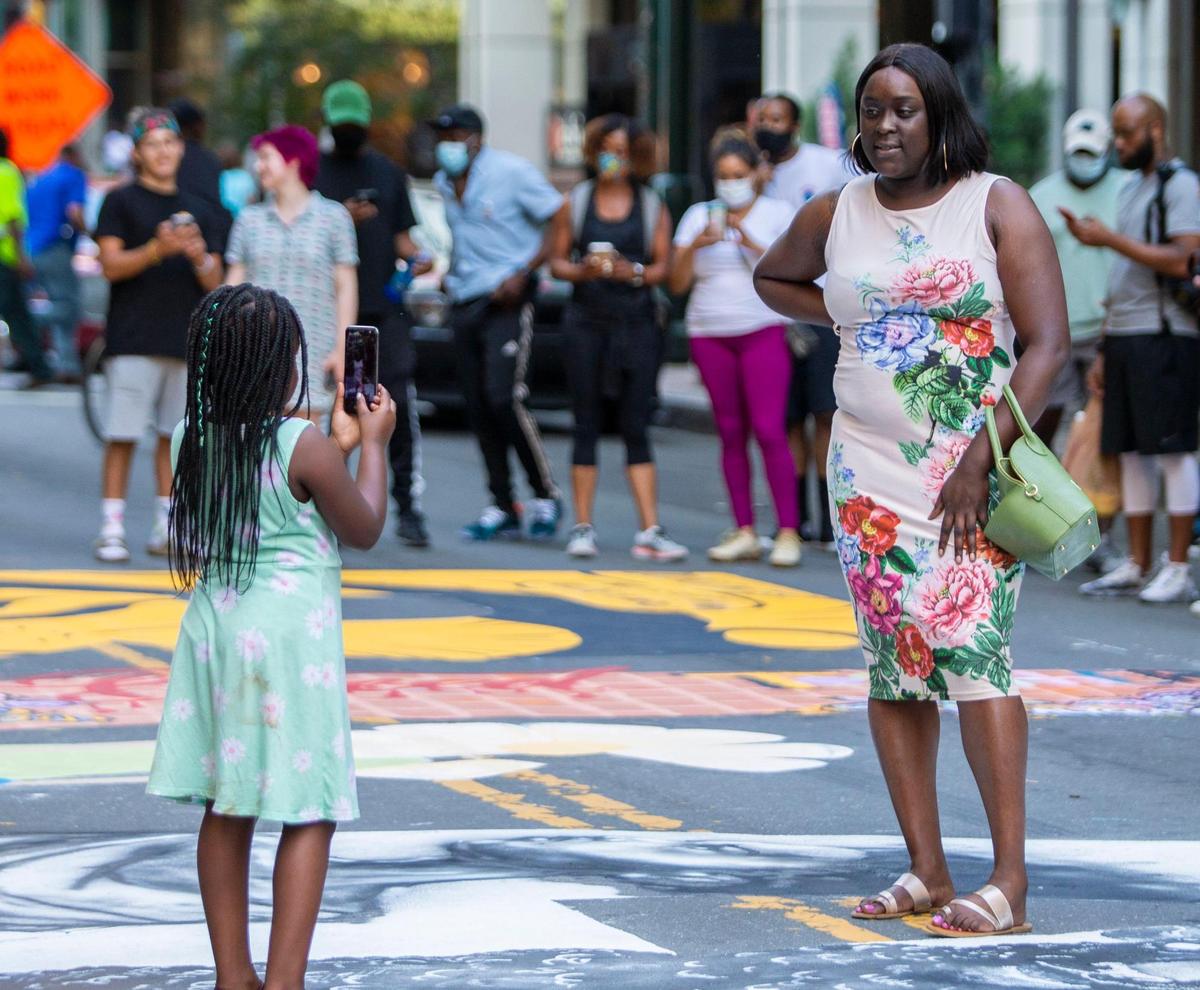 Aubrey Lytle takes a photo for her mother, Ashley Lytle after the “Black Lives Matter” street mural was completed on South Tryon Street in Charlotte, NC on Tuesday, June 9, 2020.
