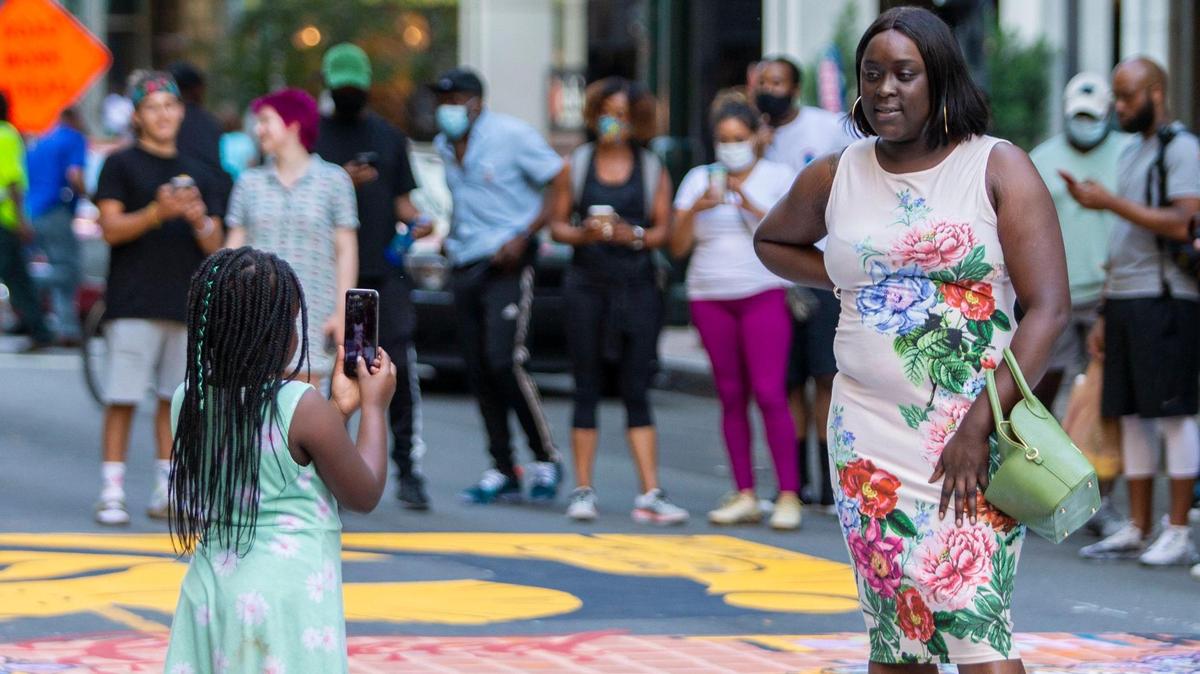 Aubrey Lytle takes a photo for her mother, Ashley Lytle after the “Black Lives Matter” street mural was completed on South Tryon Street in Charlotte, NC on Tuesday, June 9, 2020.