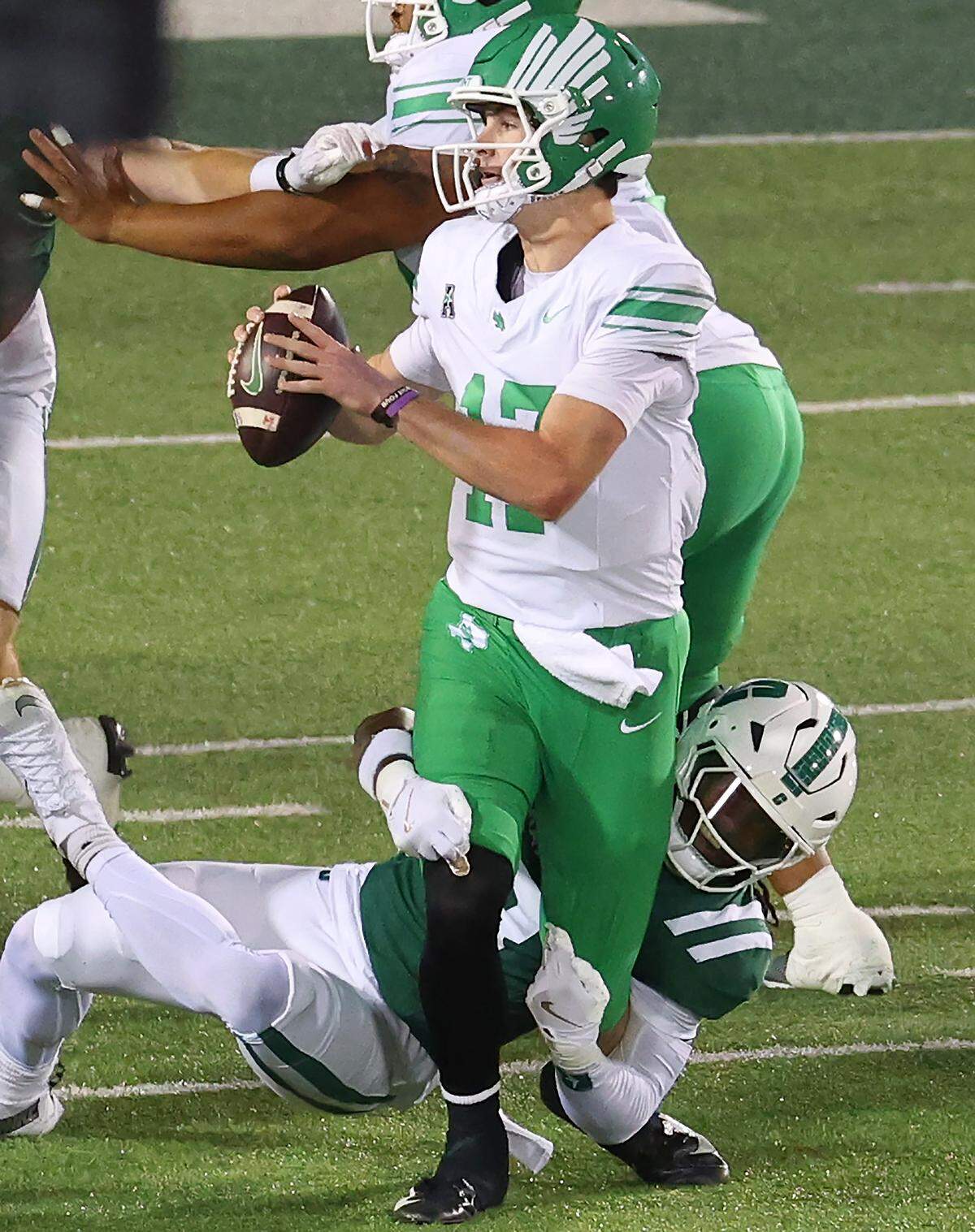 Charlotte 49ers defensive back Collin Gill, bottom, wraps his arms around the legs of North Texas quarterback Drew Mestemaker during action on Friday, October 24, 2025 at Jerry Richardson Stadium.