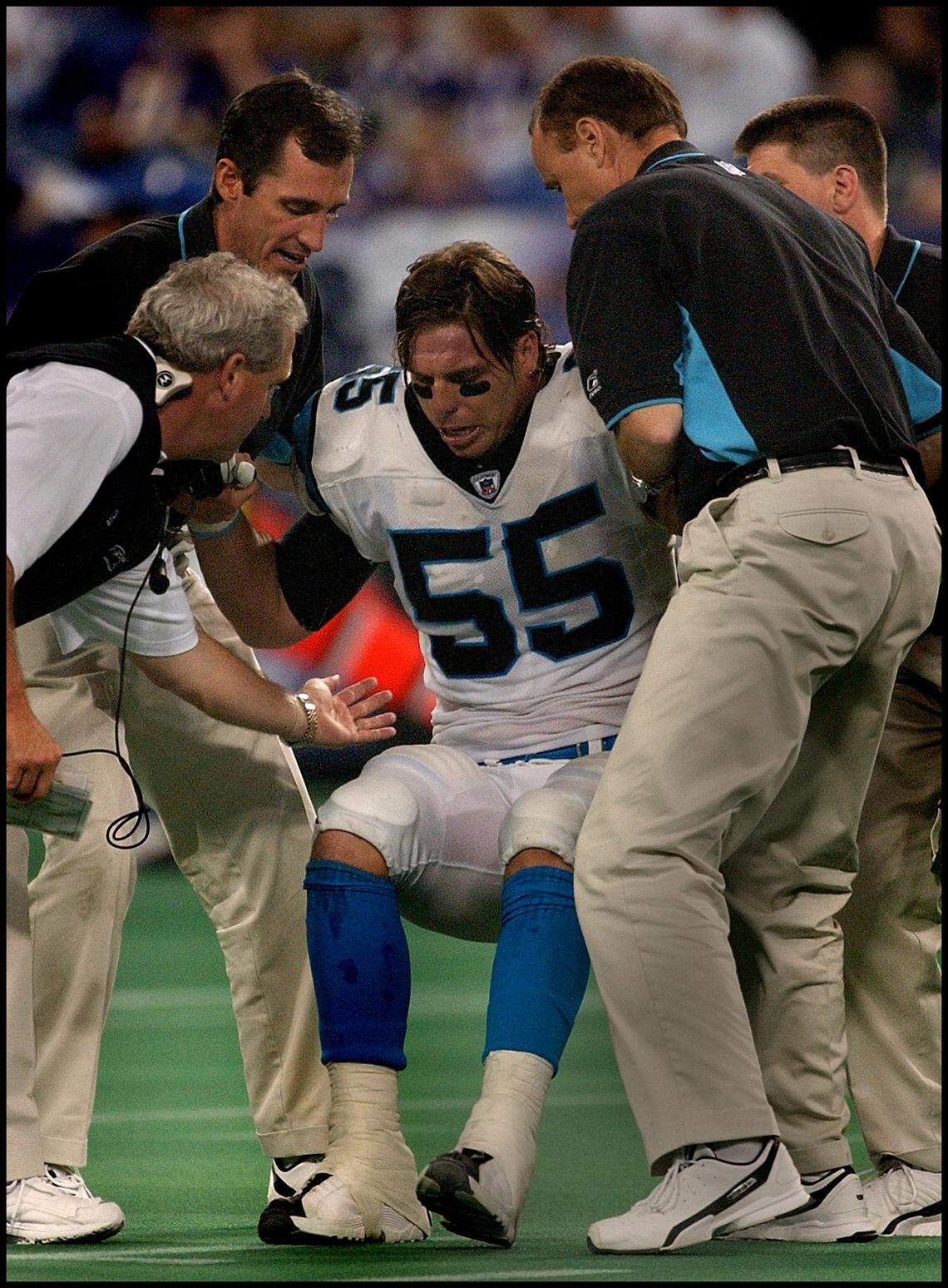 In 2002, Panthers linebacker Dan Morgan was helped to his feet after an injury by a member of the team’s training staff and head coach John Fox (left).