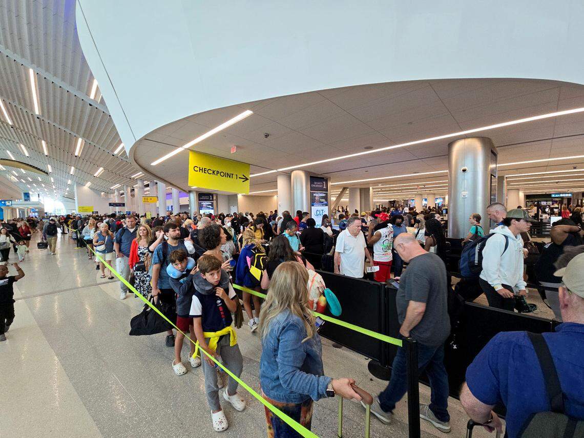 Air passengers wait in line to go through security check-in at Charlotte Douglas International recently. The airport is expecting fewer travelers than last summer.