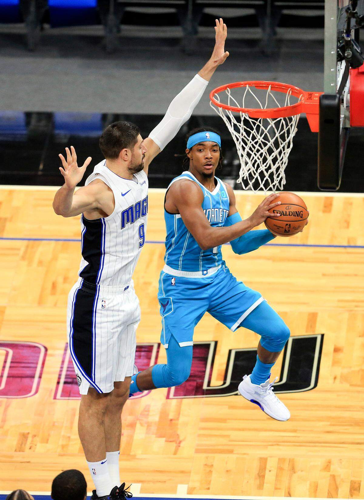 Charlotte Hornets guard Devonte’ Graham (4) passes around Orlando Magic center Nikola Vucevic (9) during a preseason game Dec. 19th.