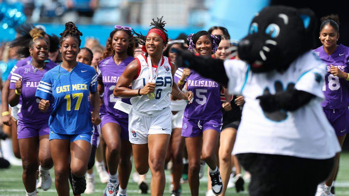 Amber Clark, center, a North Carolina native and gold-medal winning USA Football flag football athlete, leads a group of CMS flag football-playing girls out of the tunnel at Saturday’s Panthers game in Bank of America Stadium on Auguts 12, 2023.