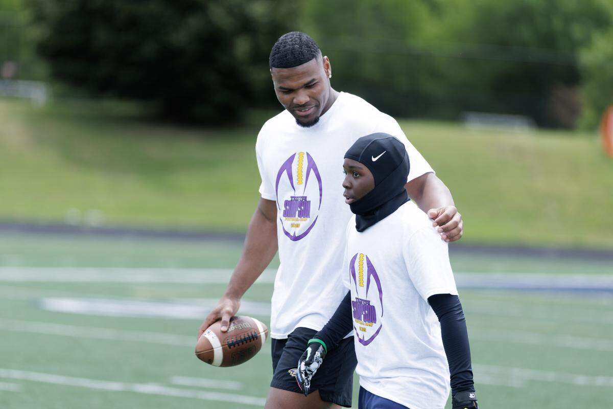 Baltimore Ravens linebacker Trent Simpson speaks with a youth player during his free football camp at Mallard Creek High School in Charlotte. Simpson was an All-American there in high school