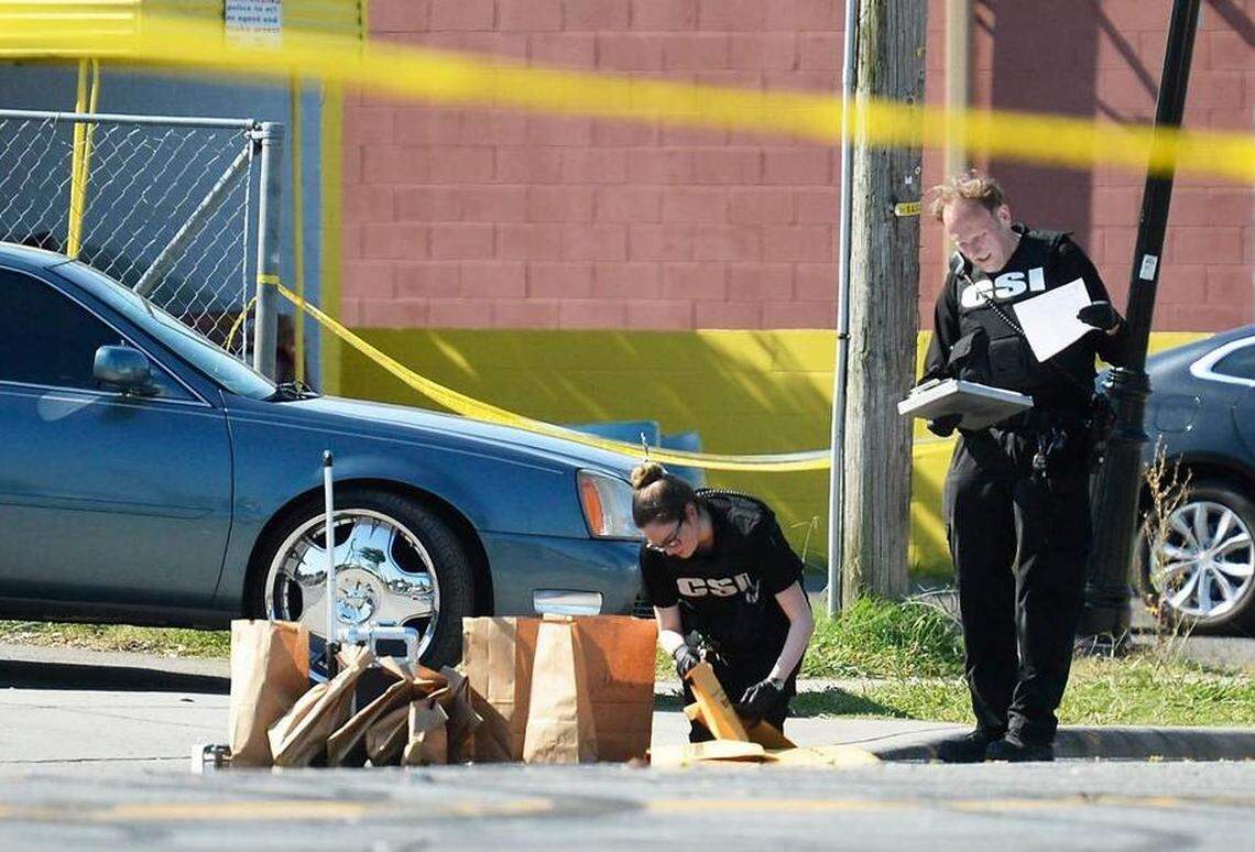 Two Charlotte-Mecklenburg Police Department crime scene investigators collect evidence following a mass shooting on Beatties Ford Road in June 2020. Four people were killed.