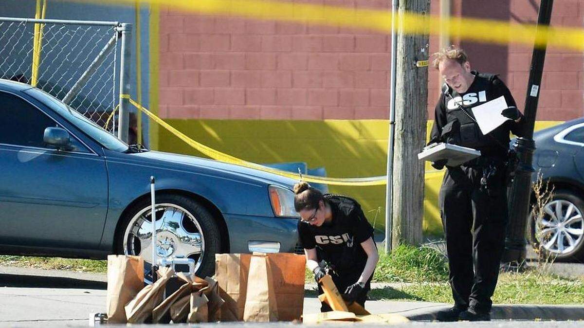 Two CMPD crime scene investigators collect evidence following a mass shooting during Juneteenth weekend on Beatties Ford Road. Four people were killed and at least 10 others struck by bullets or cars after gunfire erupted during the weekend celebration.