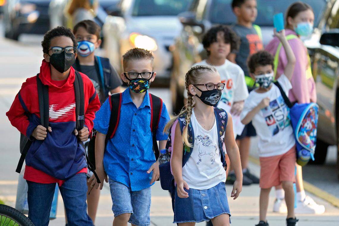 In this Tuesday, Aug. 10, 2021, file photo, students, some wearing protective masks, arrive for the first day of school at Sessums Elementary School in Riverview, Fla.