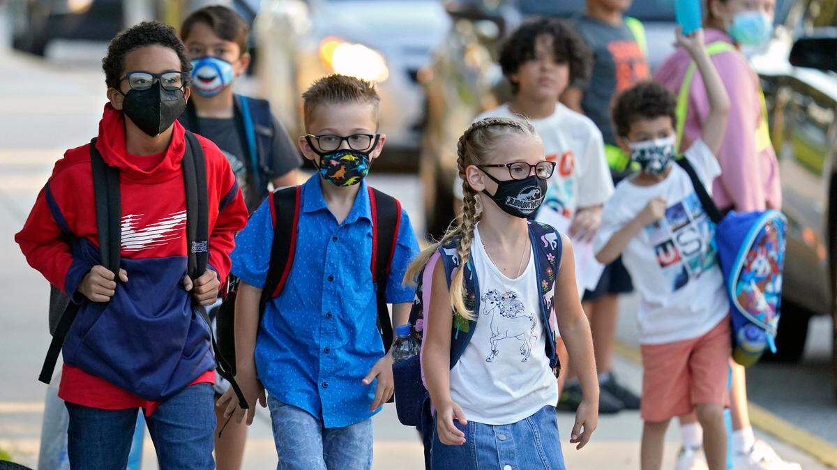 In this Tuesday, Aug. 10, 2021, file photo, students, some wearing protective masks, arrive for the first day of school at Sessums Elementary School in Riverview, Fla.