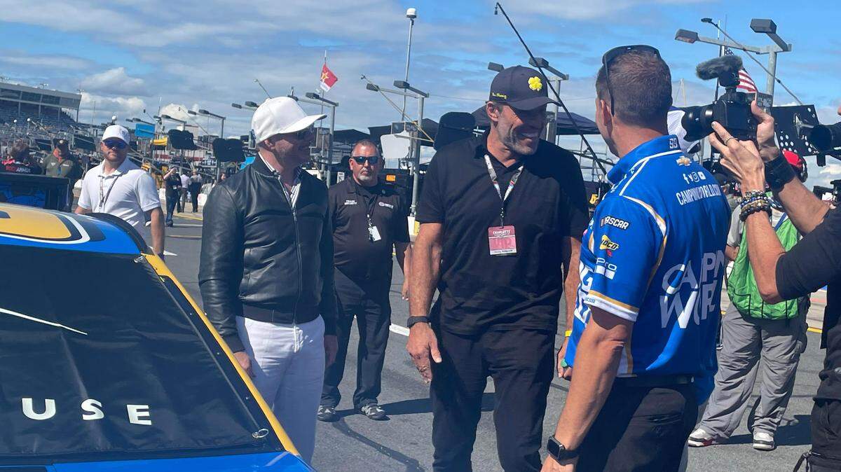 International musician Pitbull and motivational speaker Tony Robbins stand talking next to the No. 99 Trackhouse Racing Chevrolet ahead of NASCAR’s Coca-Cola 600 race at Charlotte Motor Speedway.