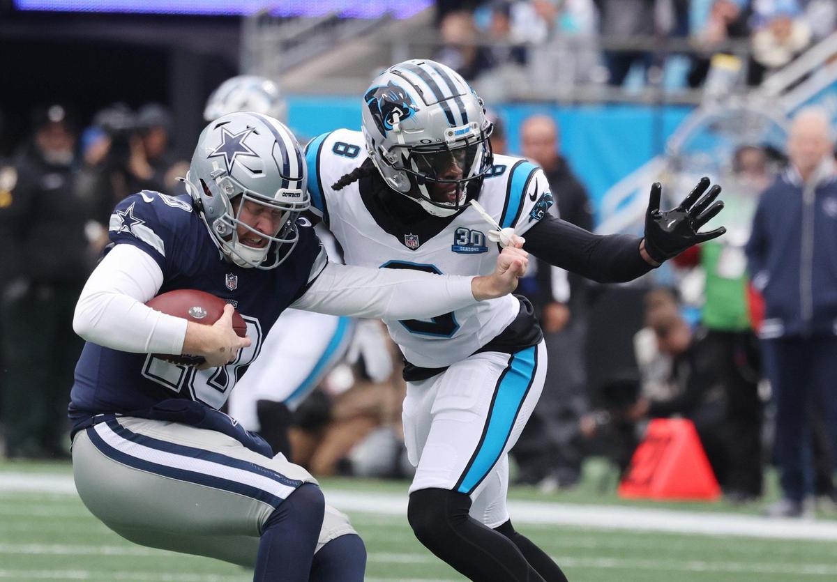 Panthers Jaycee Horn (8) tries to take down Cowboys QB Cooper Rush.